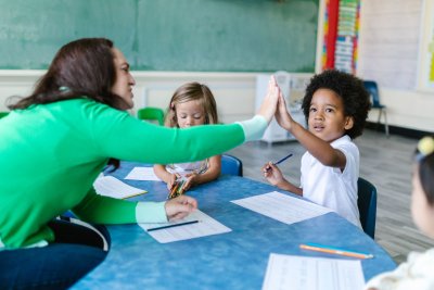 An adult and young person in conversation over a piece of work or assignment, with a calm, supportive tone
