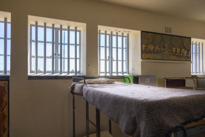 Interior view of a prison cell door with metal bars, showing institutional confinement