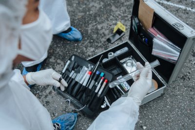 A forensic scientist in a laboratory examining DNA samples under controlled conditions, with equipment and test tubes visible