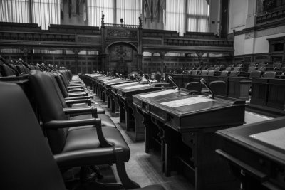 Interior view of a parliament or legislative chamber with tiered seating, formal architecture, and empty or partially occupied benches